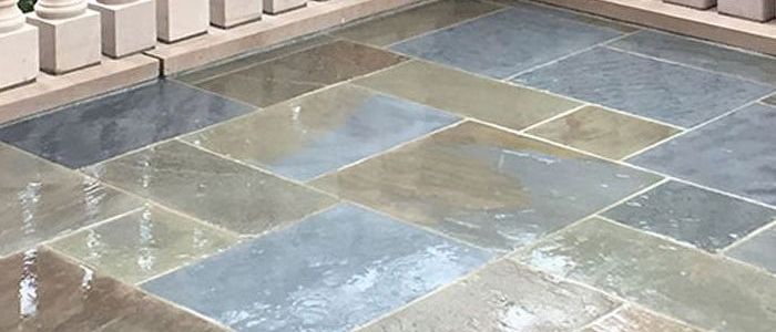 A close up of a tiled floor with a fence in the background.
