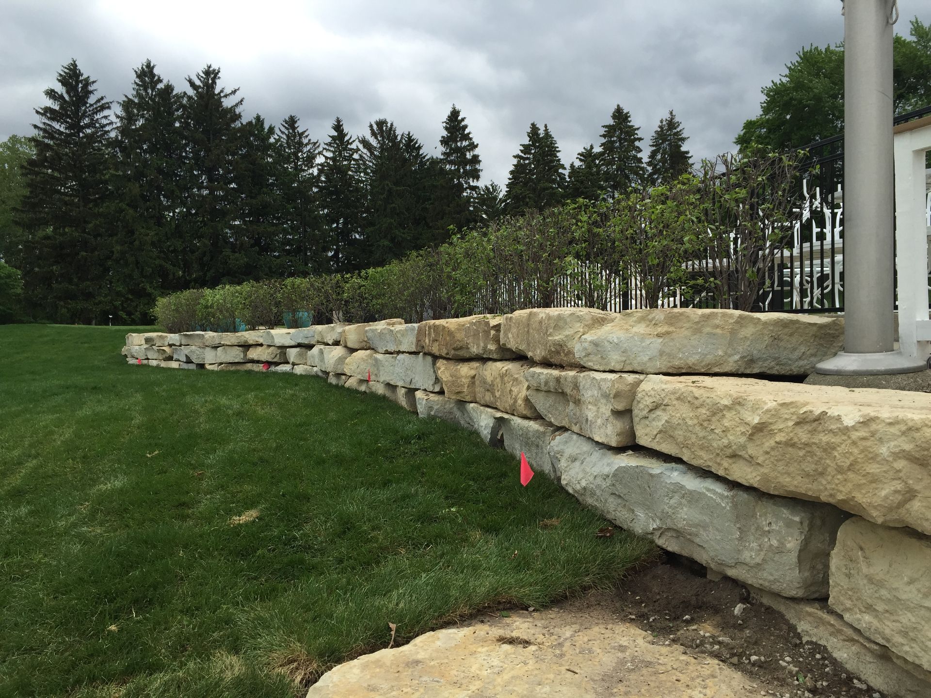 A large stone wall surrounds a lush green lawn.