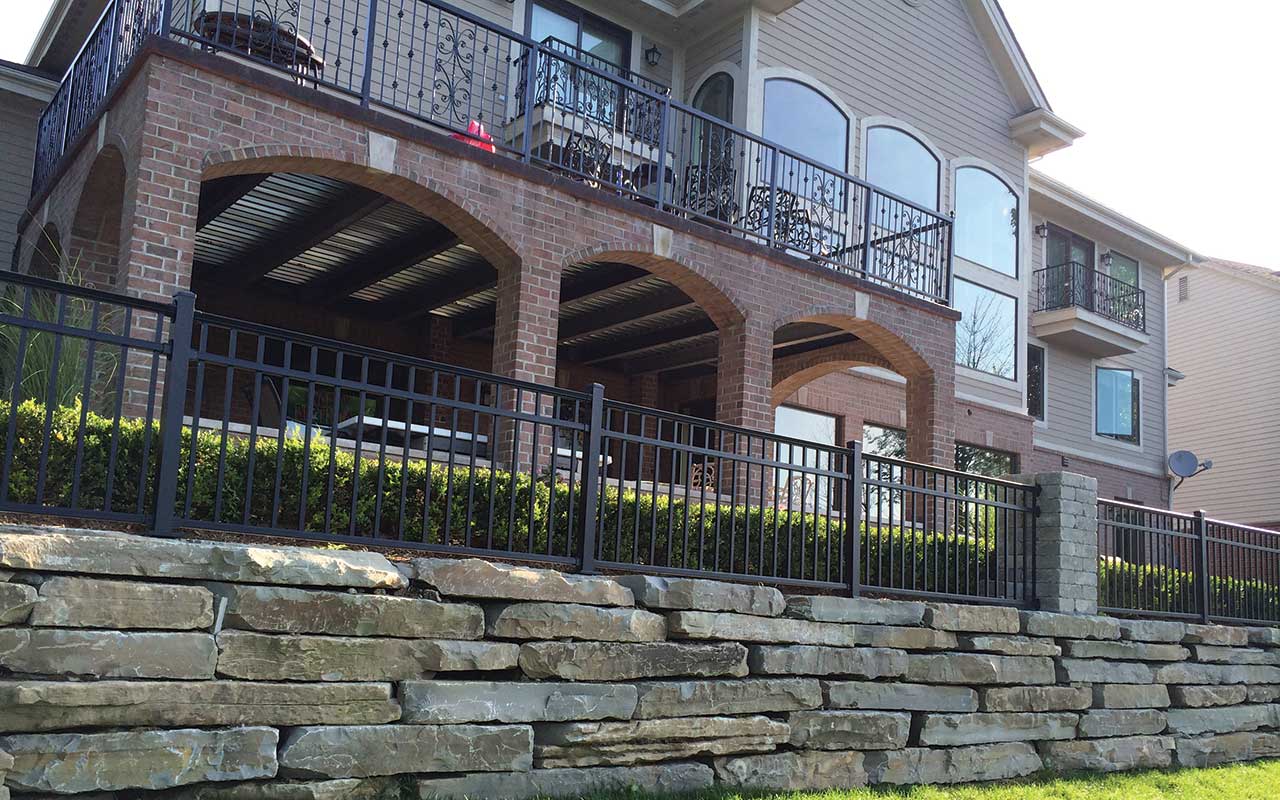a large house with a balcony and a stone wall behind it .