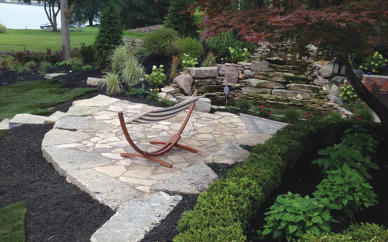 a rocking chair is sitting on a stone patio in a garden .