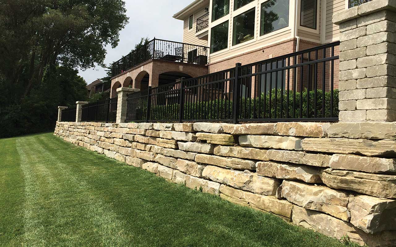 there is a large stone wall in front of a house .