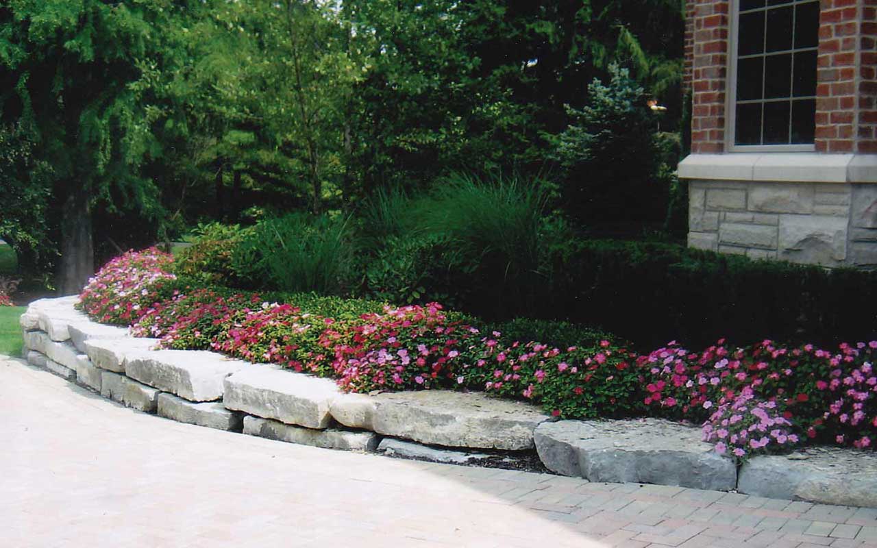 a brick building with a stone wall and flowers in front of it