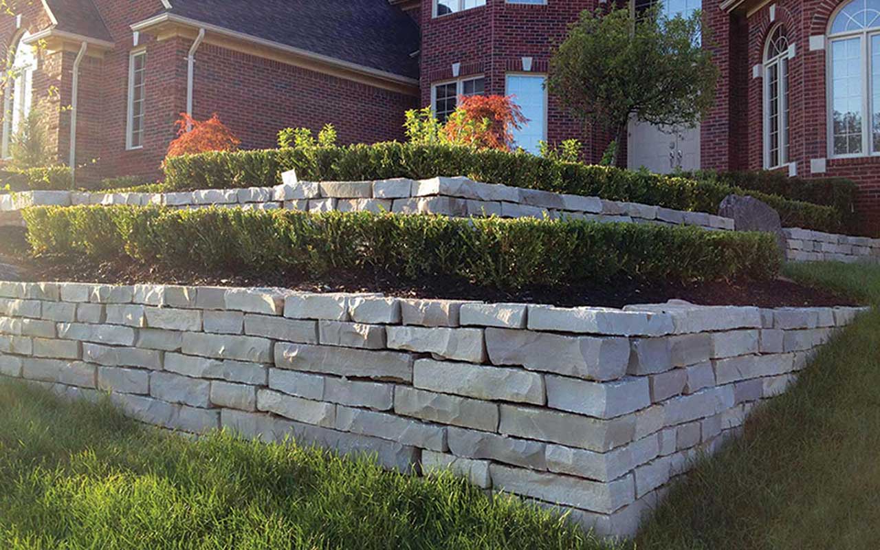 a large stone wall is in front of a brick house .