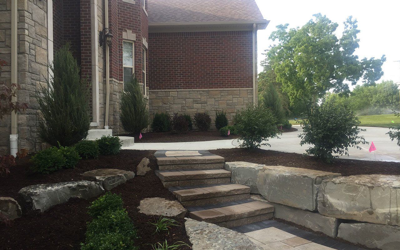 a stone walkway leading up to a brick house .