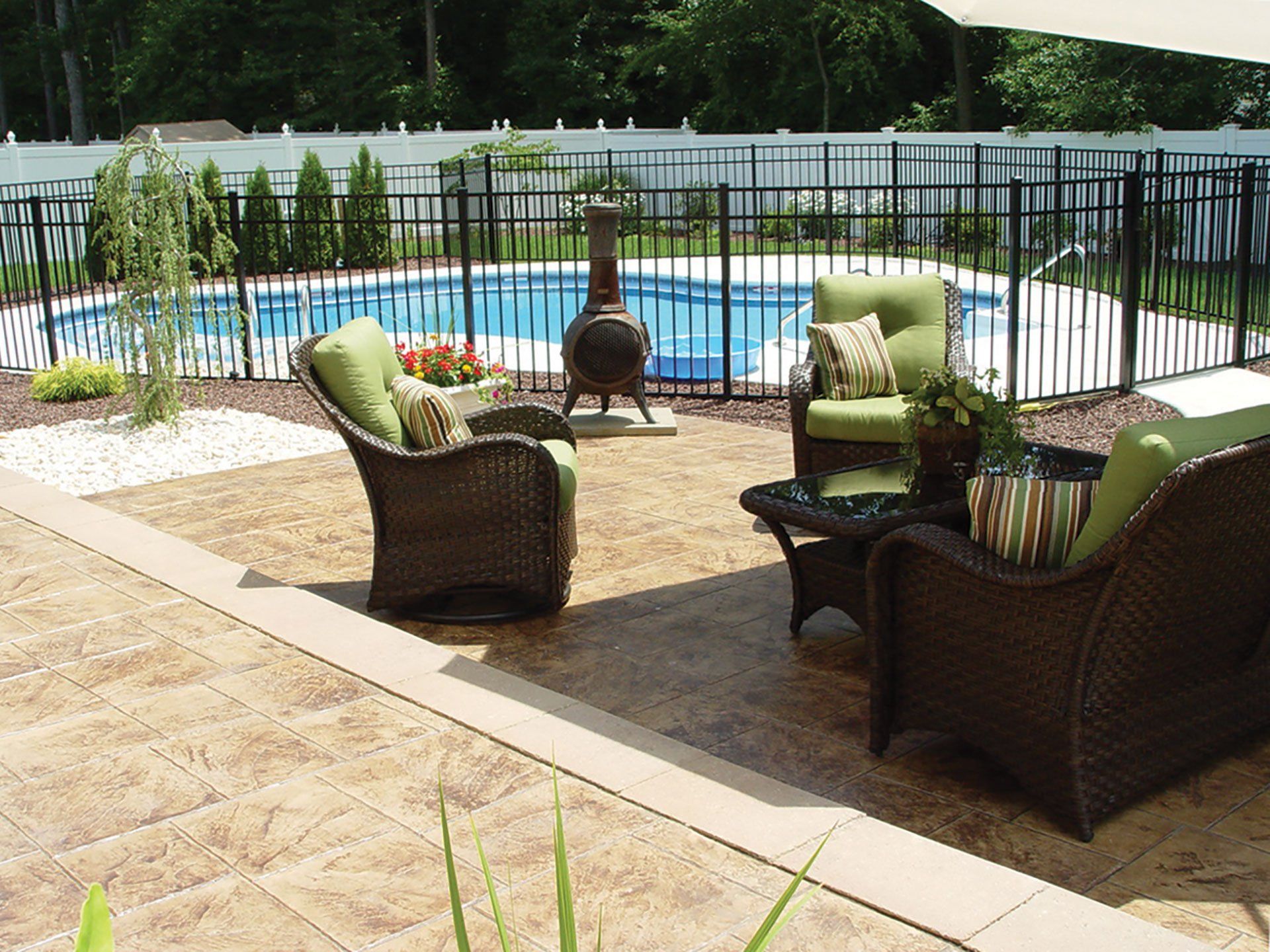 a patio with chairs and a table in front of a pool