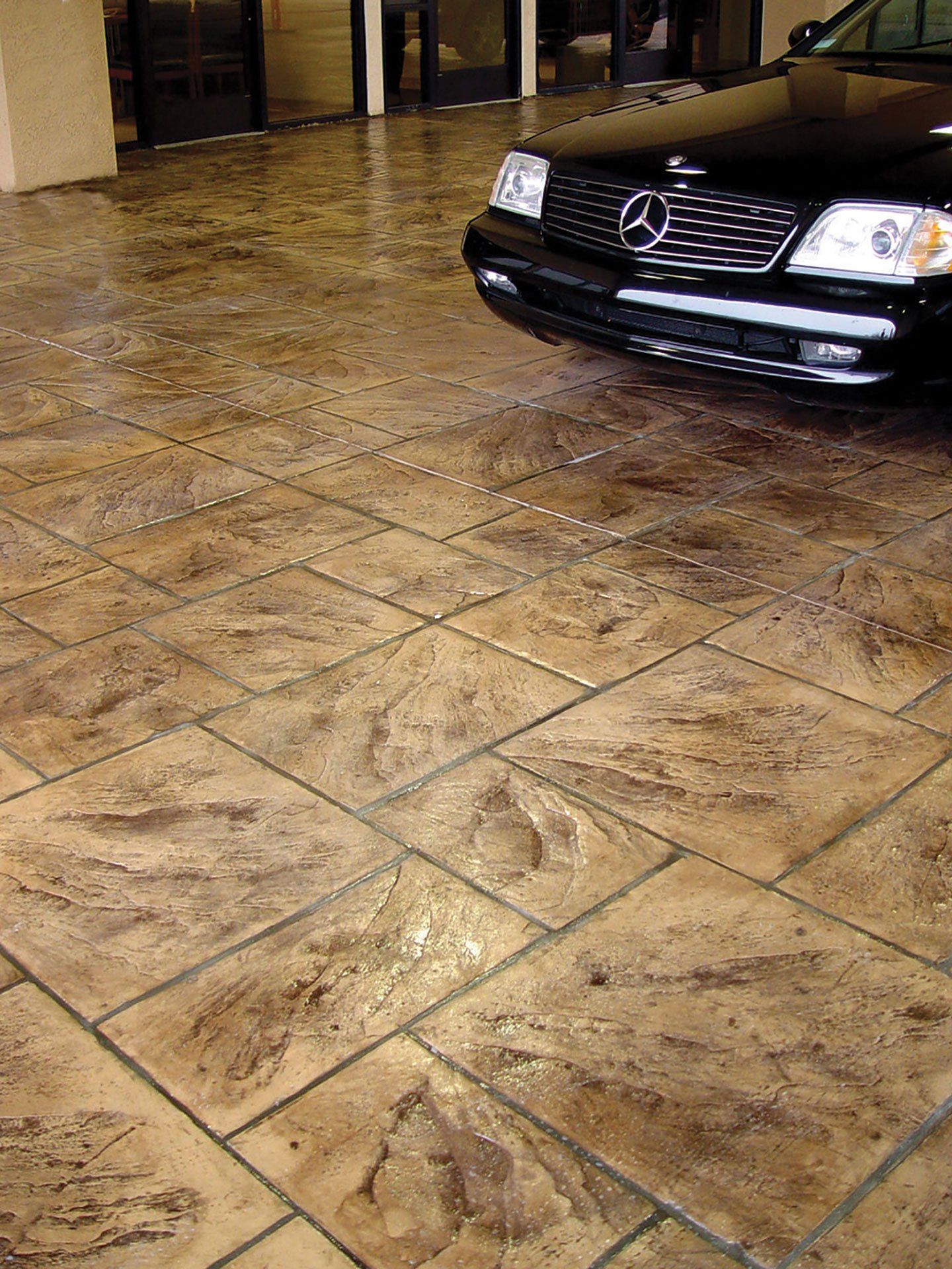 a black mercedes is parked on a tiled driveway .