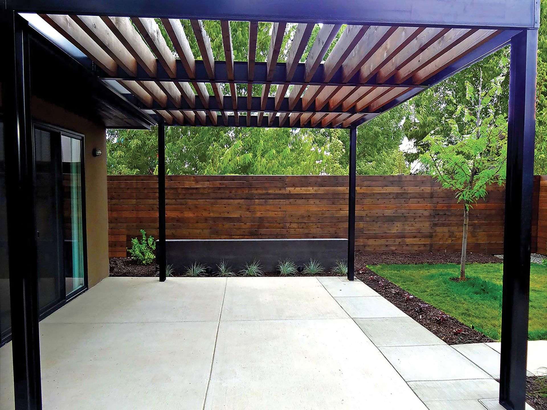 a patio with a pergola and a wooden fence