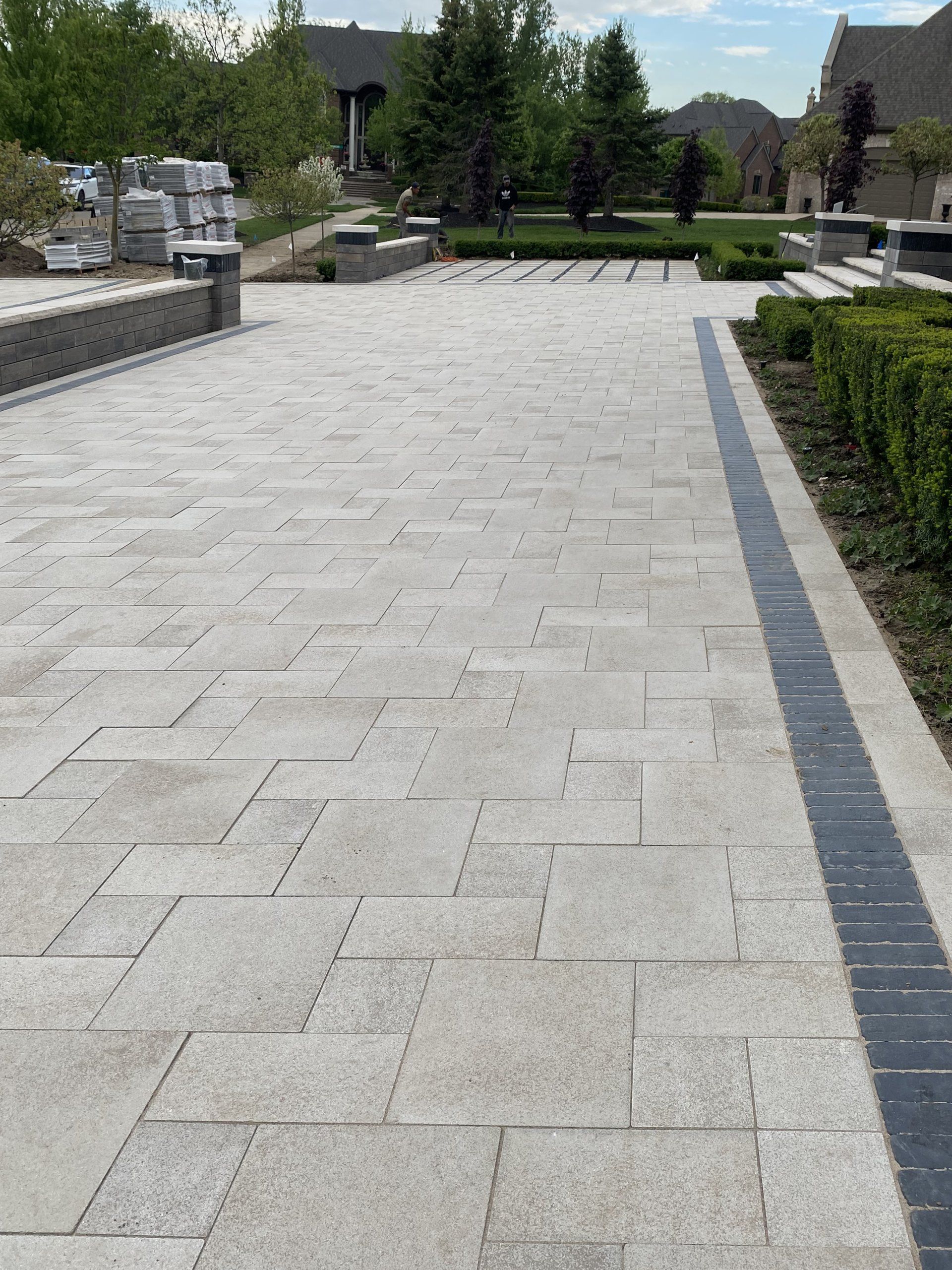 a brick walkway leading to a house with trees in the background