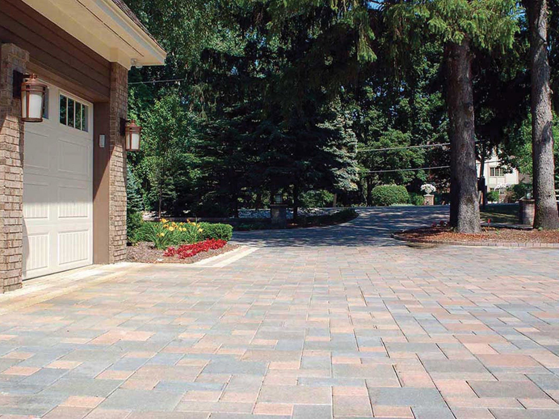 A brick driveway leading to a garage with trees in the background