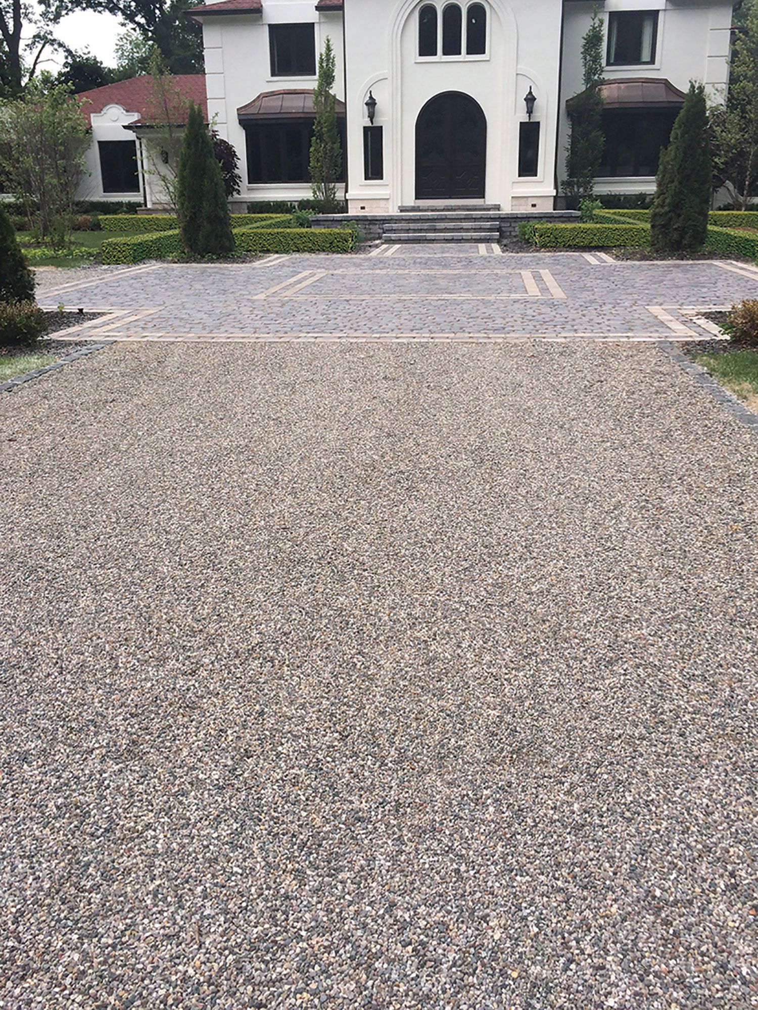 a gravel driveway leading to a large white house .