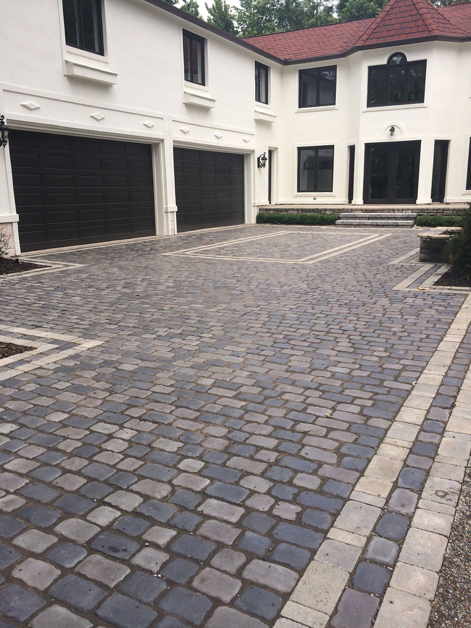 a large white house with a brick driveway in front of it .