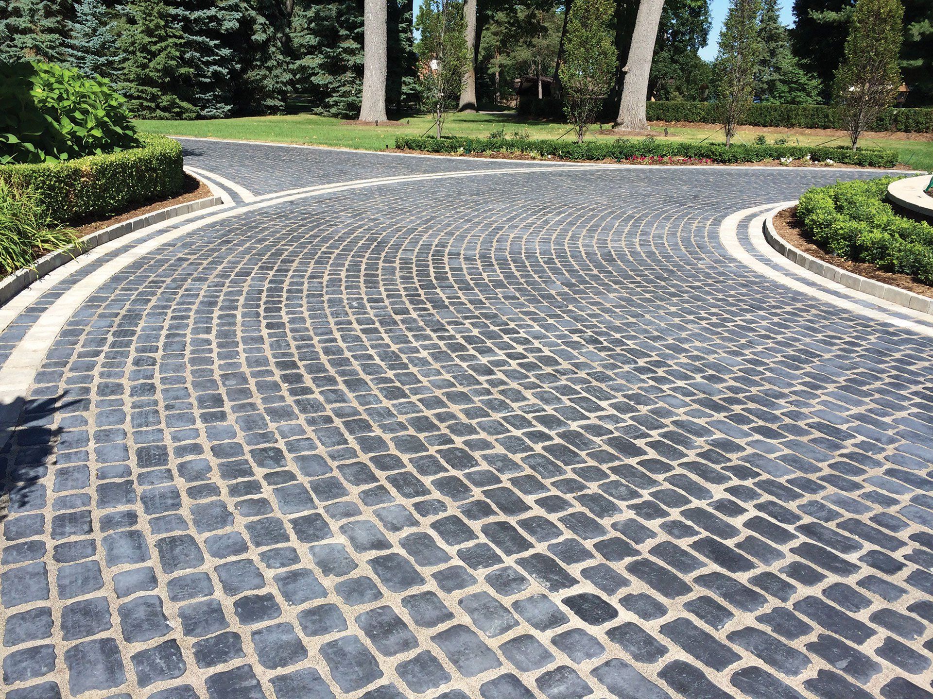 a cobblestone driveway with a curve in the middle