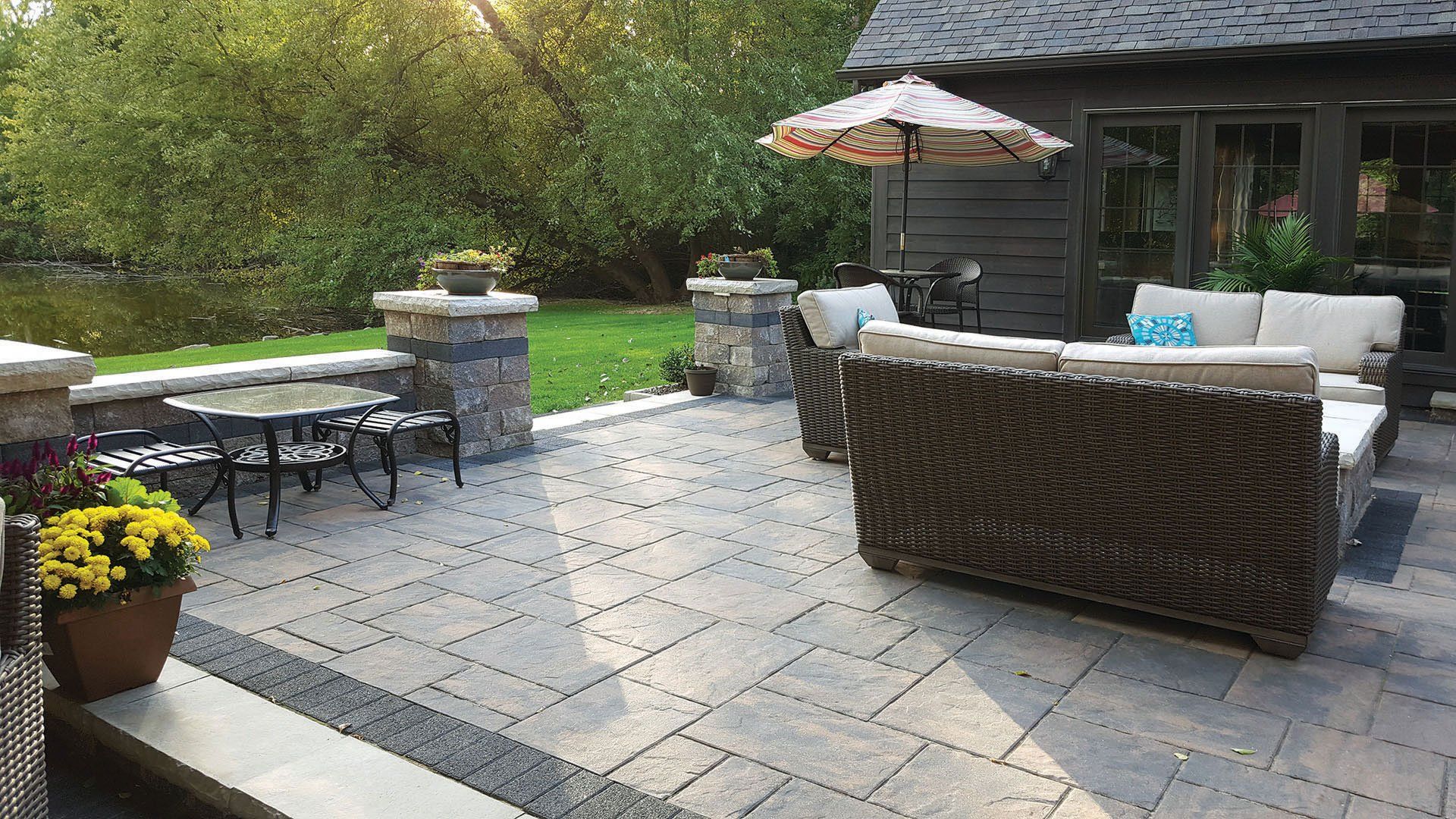a patio with a couch , table and umbrella in front of a house .
