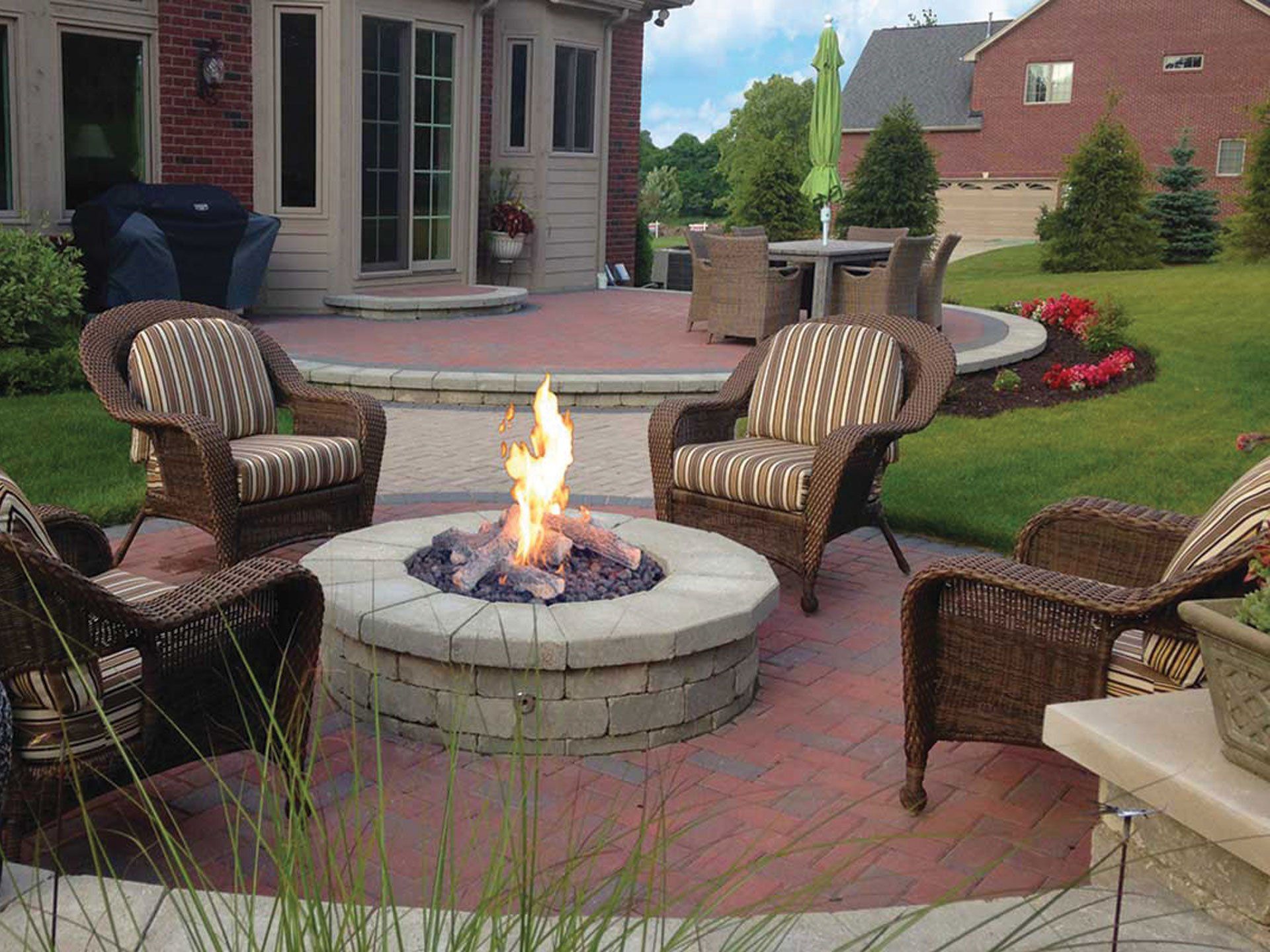 a fire pit in the middle of a patio with chairs around it