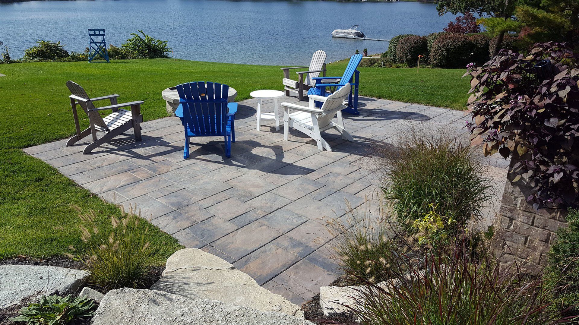 a group of chairs are sitting on a patio next to a lake .