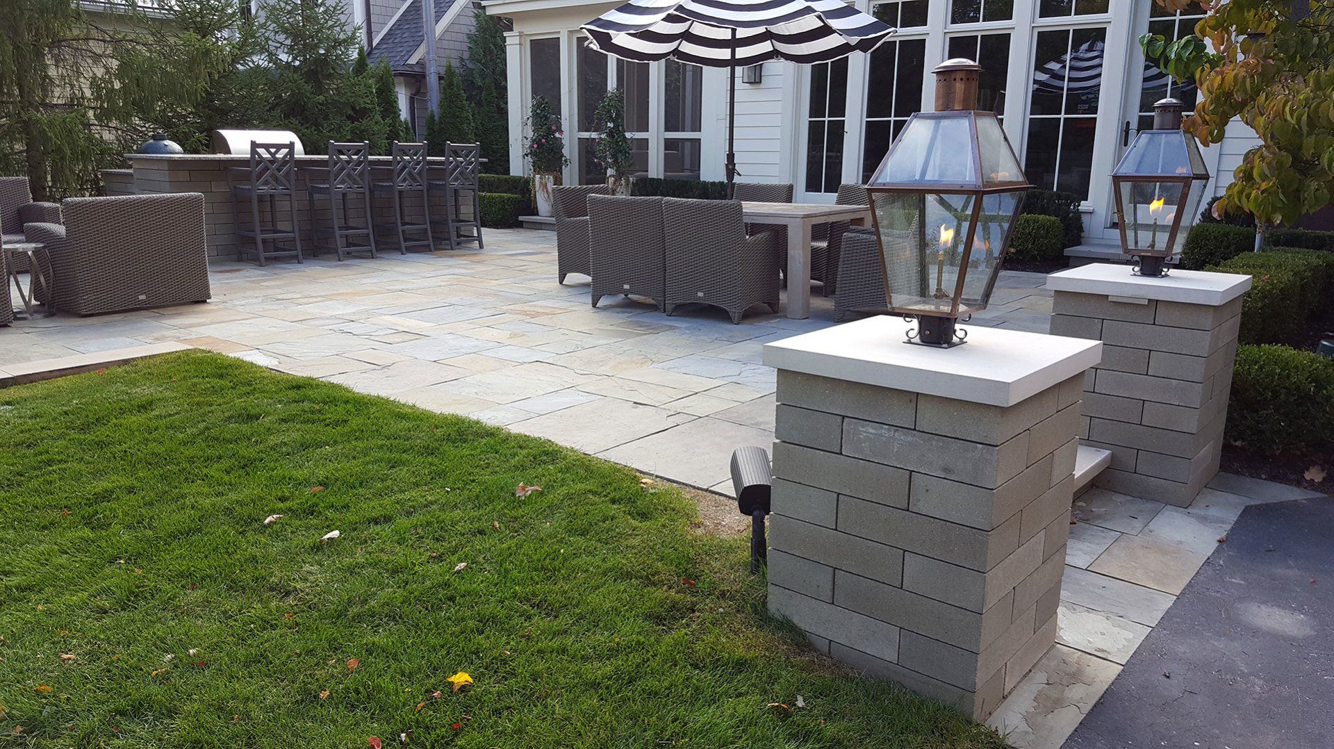 a patio with umbrellas and lanterns in front of a house