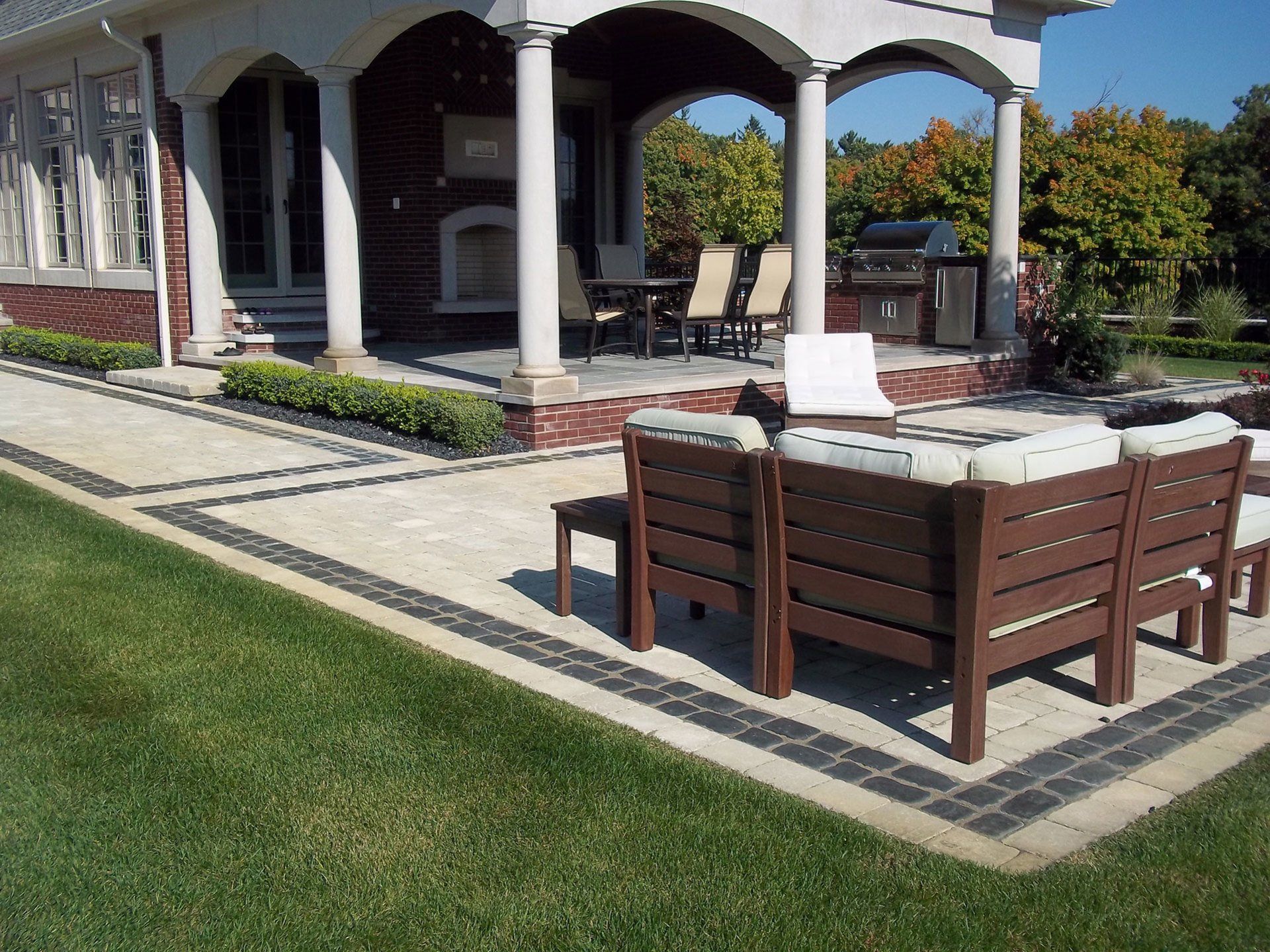 a patio with a couch and chairs in front of a house