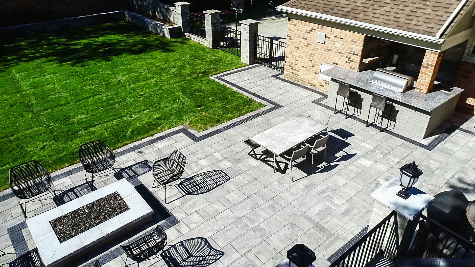 An aerial view of a patio with a fire pit , tables and chairs.