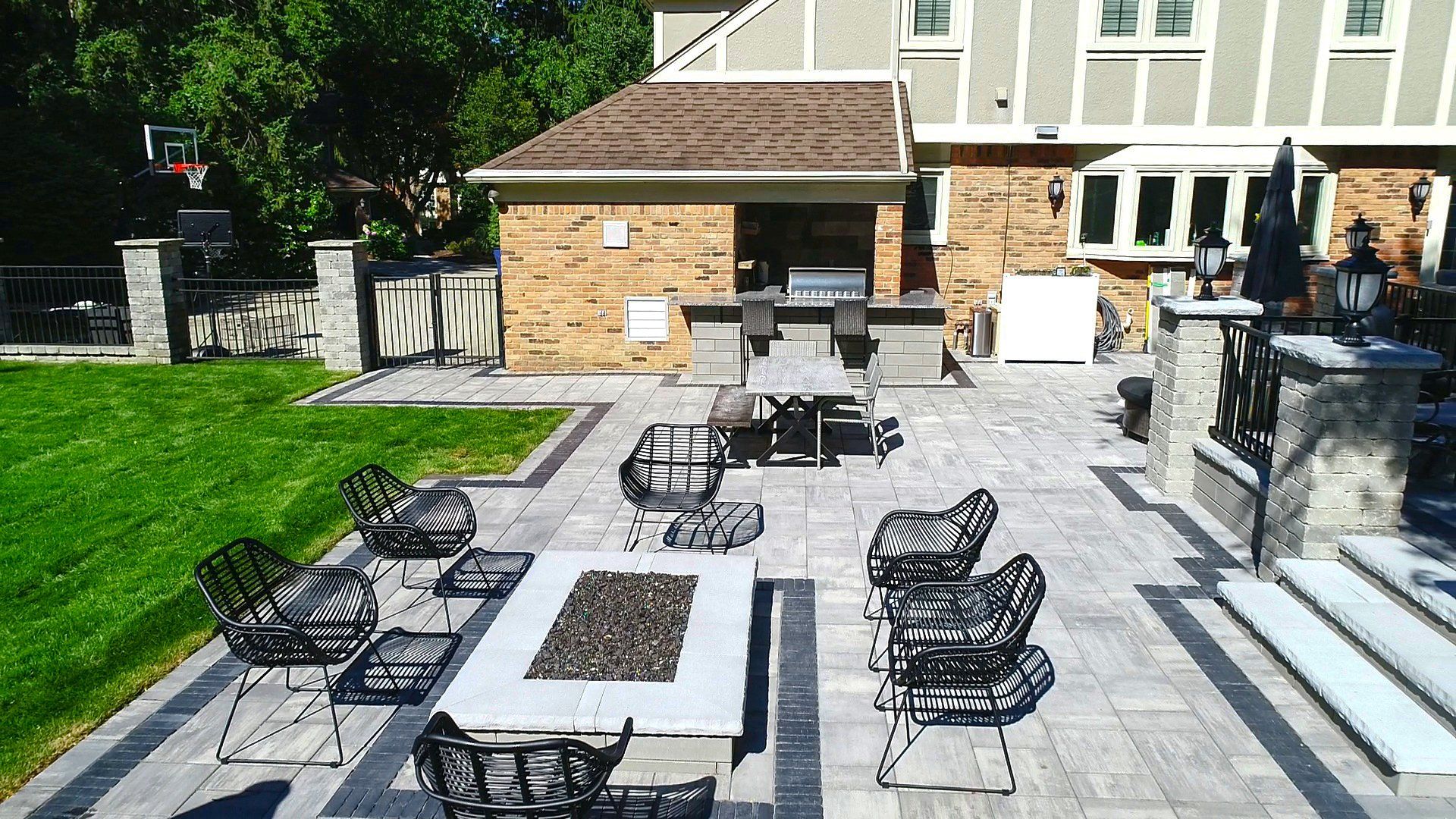 A patio with a fire pit and chairs in front of a house.
