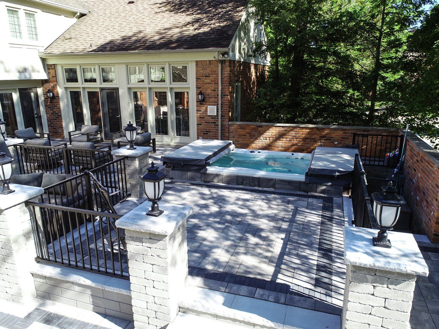 A patio with a hot tub and a brick building in the background