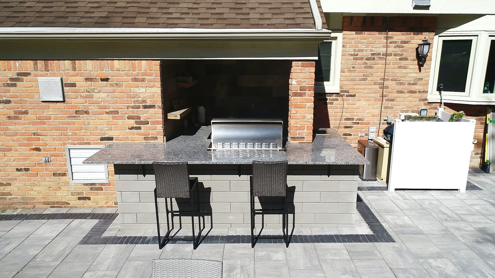 A brick house with a patio area with a grill and chairs