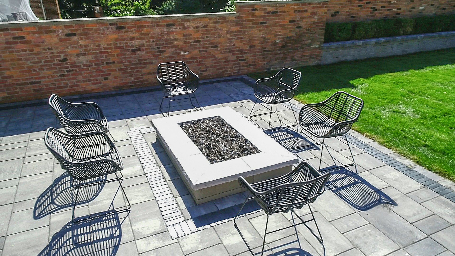 There is a fire pit on the patio with chairs around it.