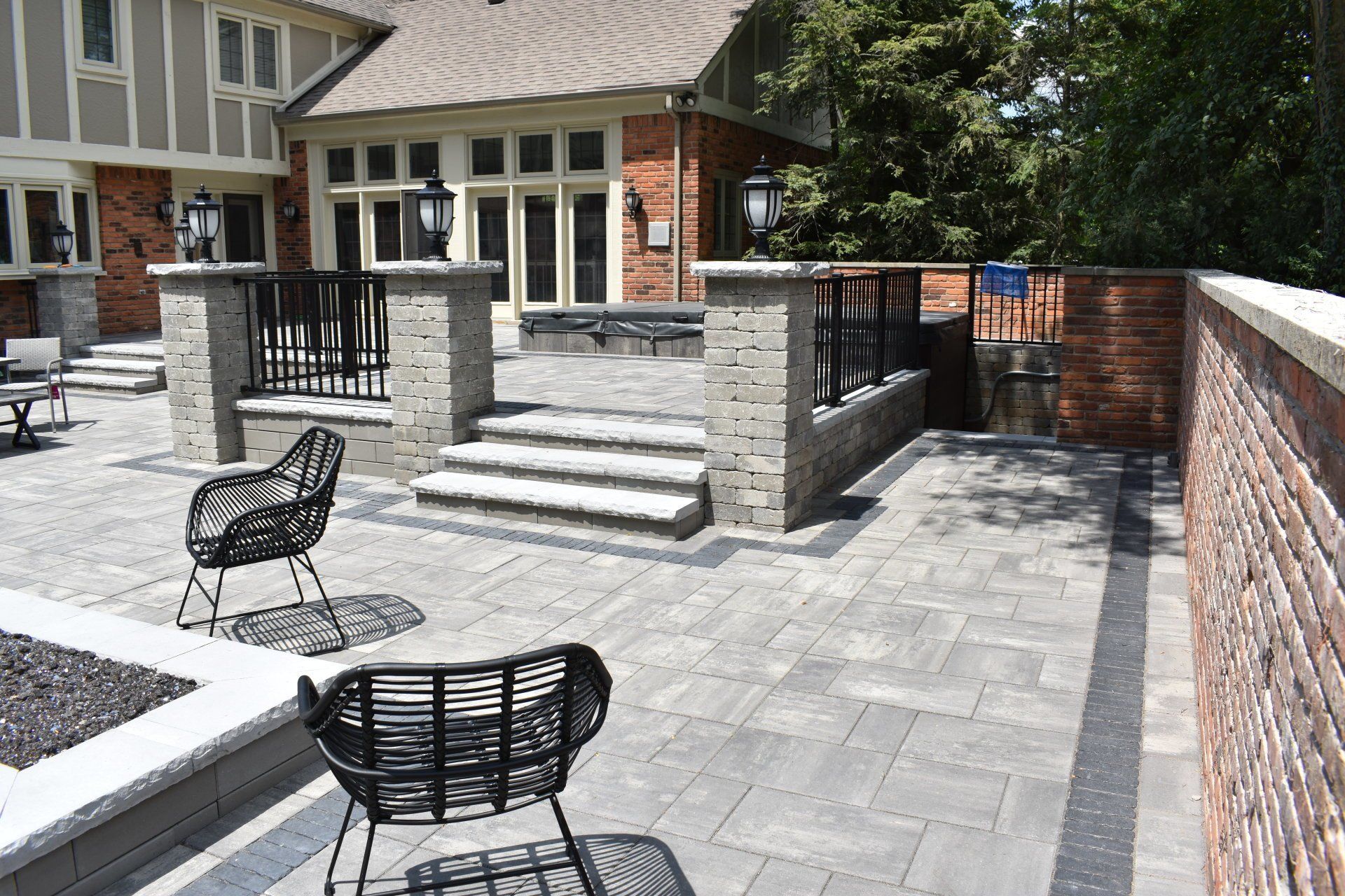 A patio with chairs and a brick wall in front of a house.