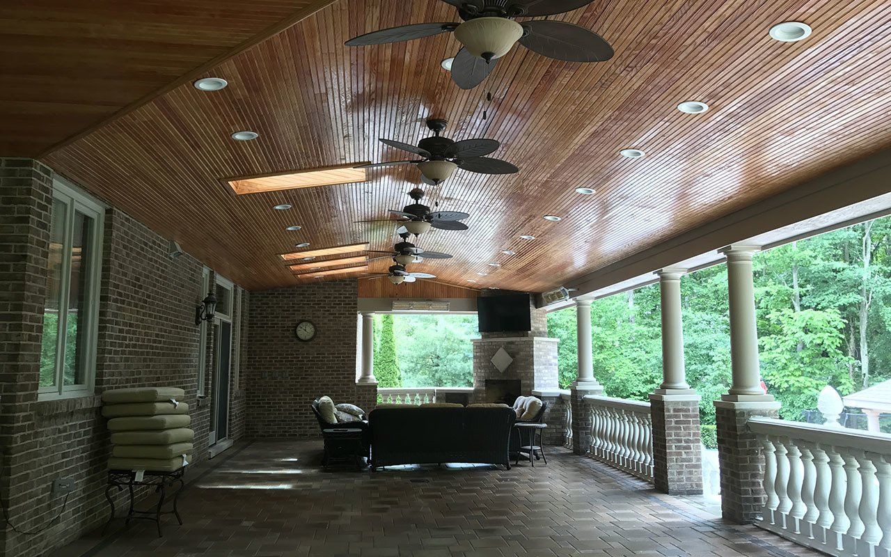 a large porch with a wooden ceiling and ceiling fans .