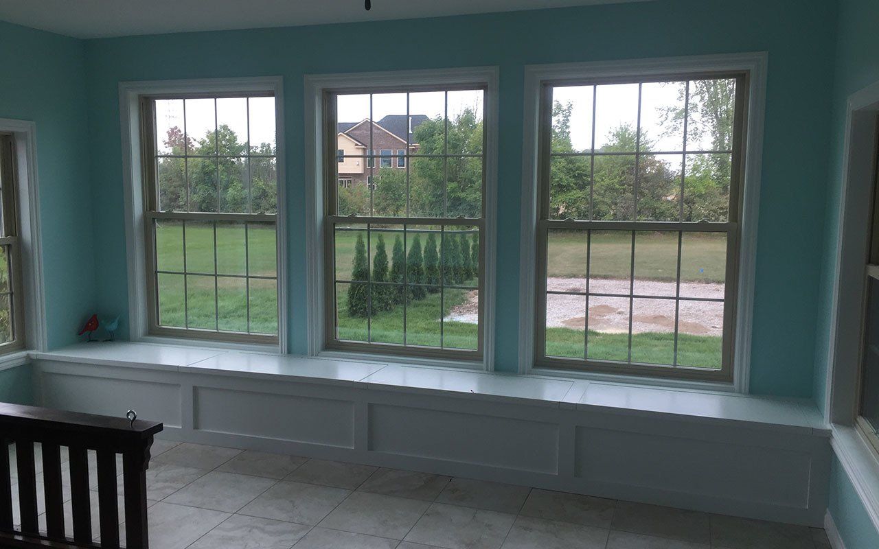 a room with three windows and a bench in the middle