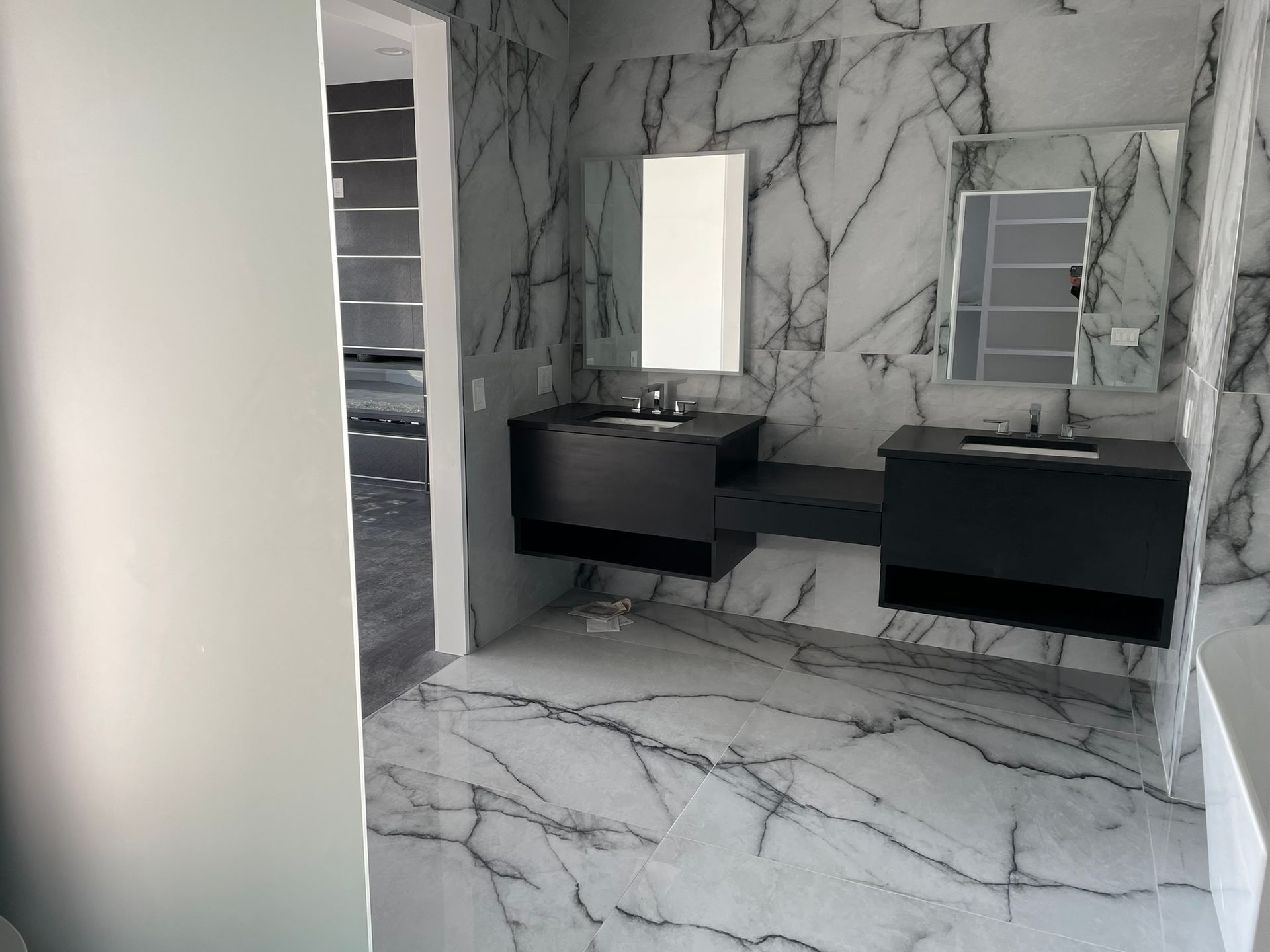 A bathroom with two sinks , a mirror and a marble floor.