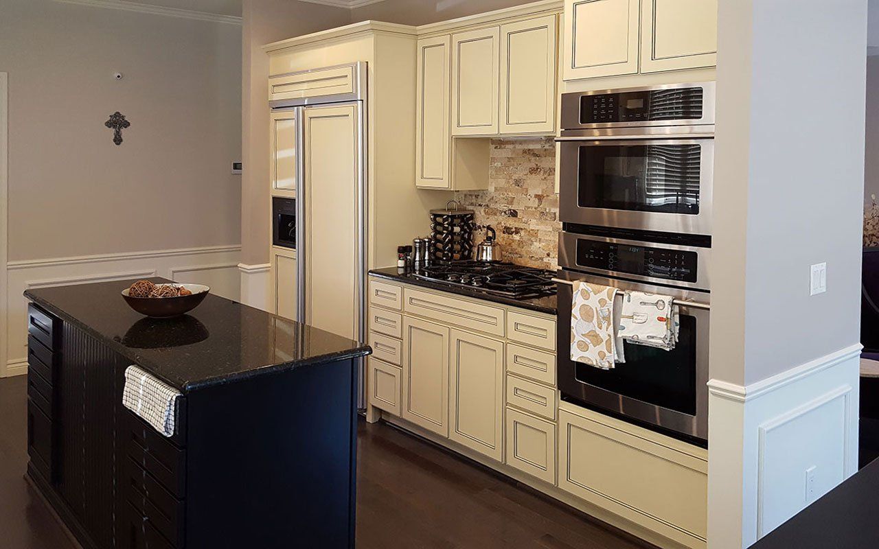 A kitchen with white cabinets, stainless steel appliances, and a black island.