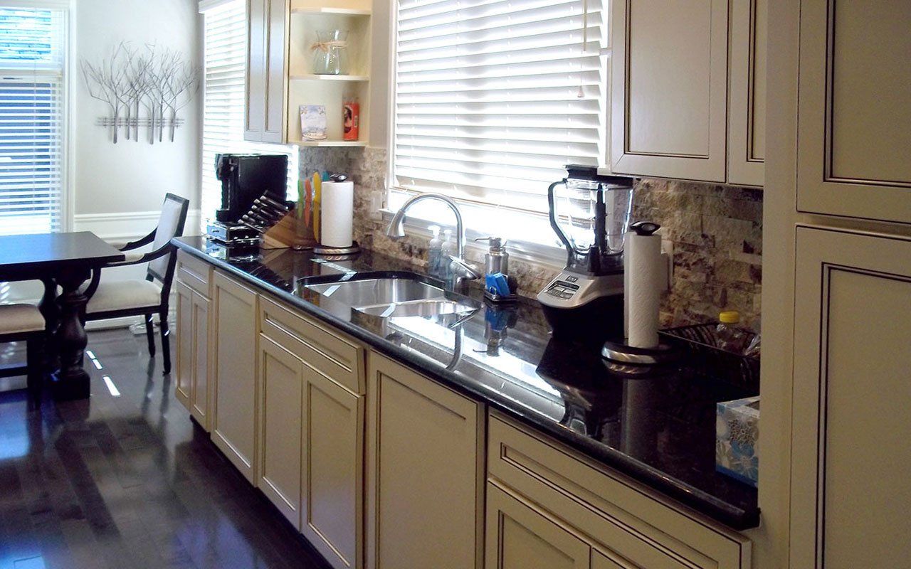 A kitchen with white cabinets and black counter tops