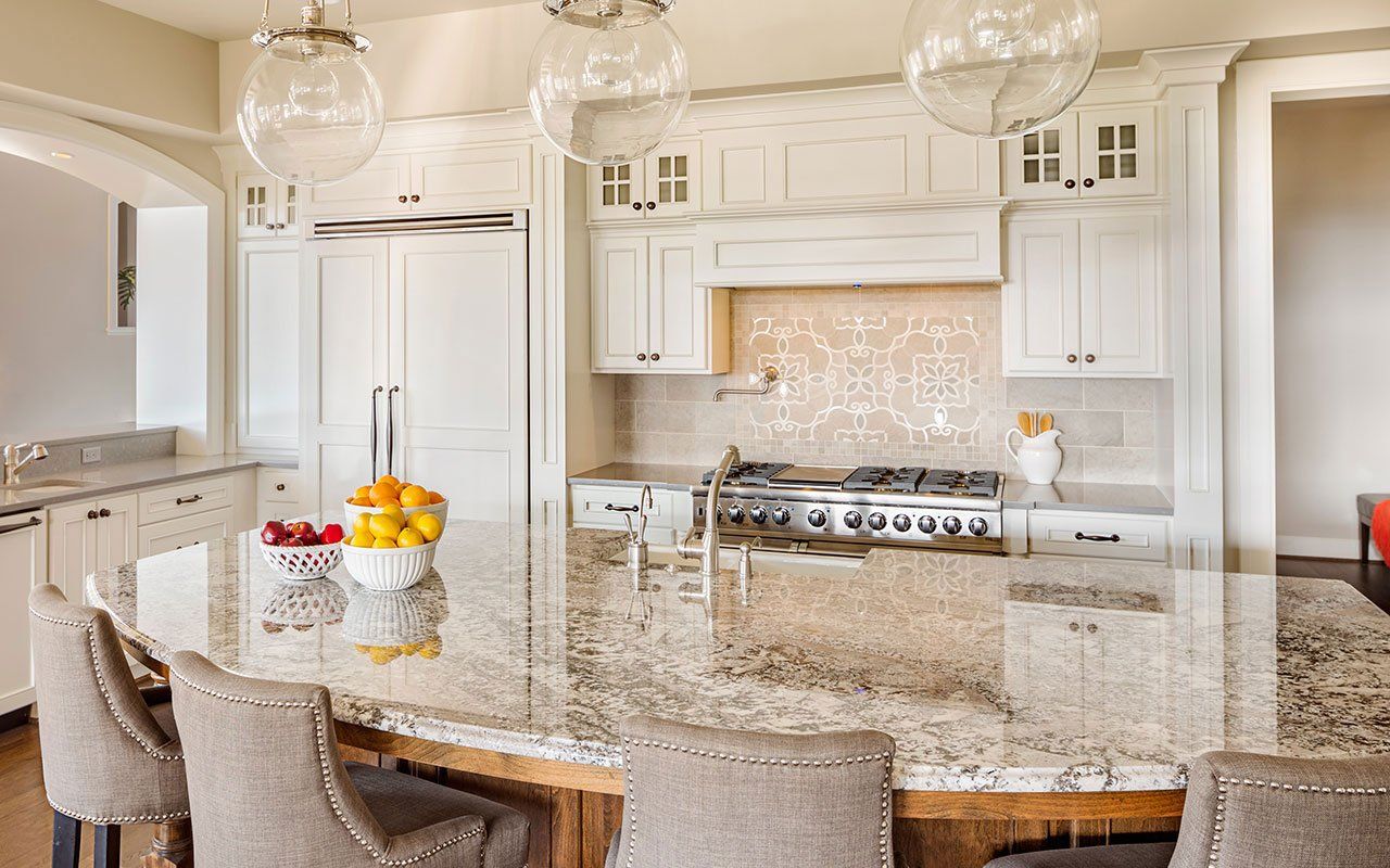 A kitchen with white cabinets, granite counter tops, a table, and chairs.