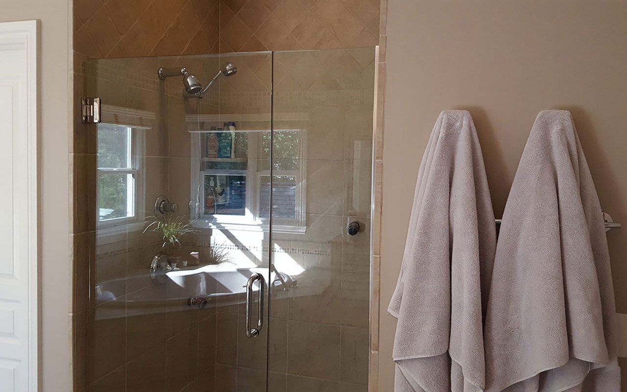 A bathroom with a glass shower door and two towels hanging on the wall.