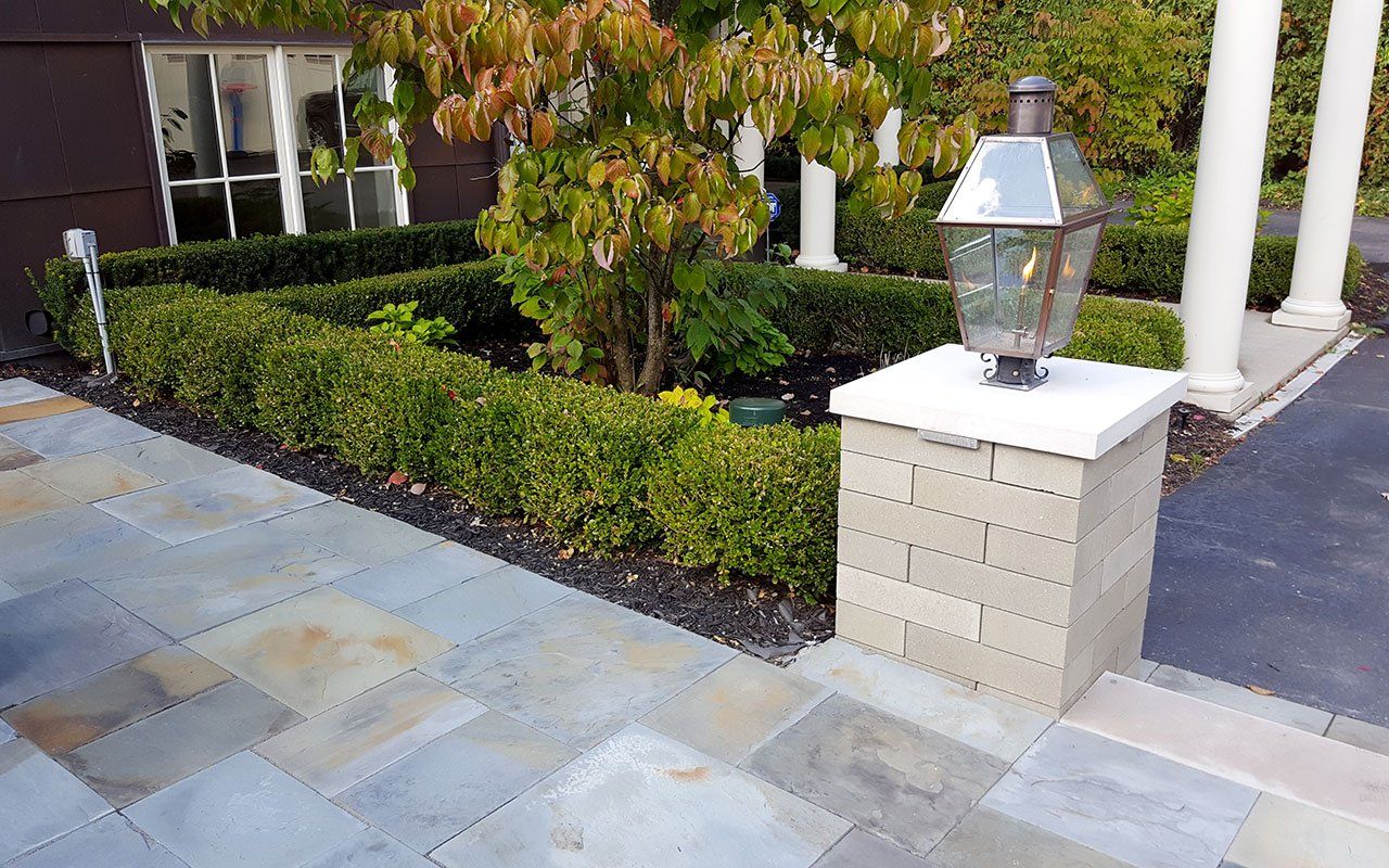 a brick pillar with a lamp on top of it in front of a house .
