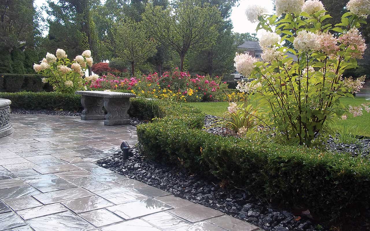 a patio with flowers and bushes in a garden