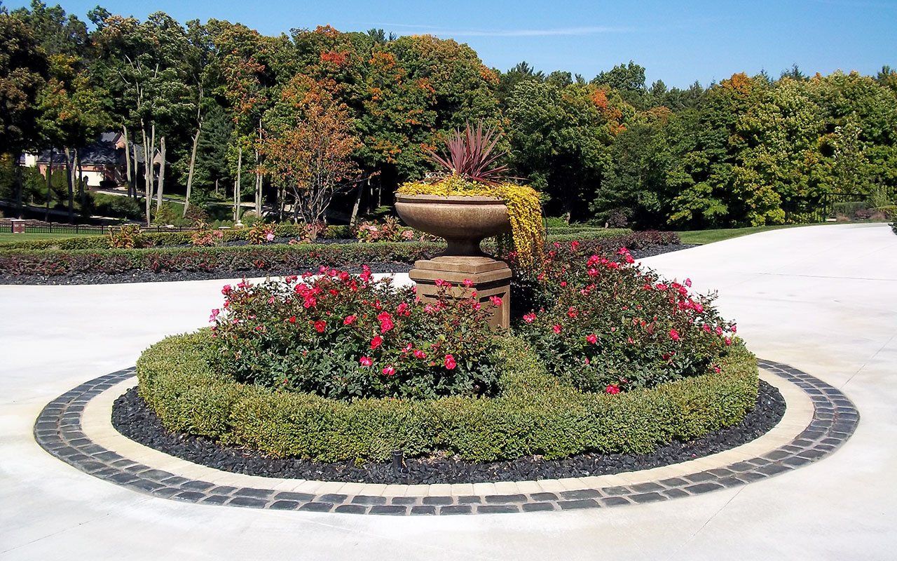 a circular garden with flowers and a vase in the middle