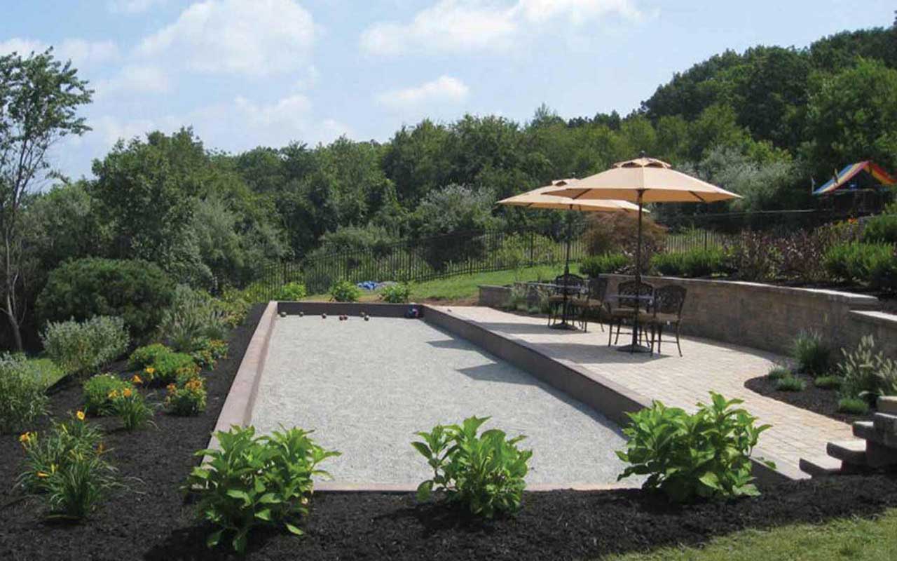 a bocce ball court with umbrellas and chairs in the background