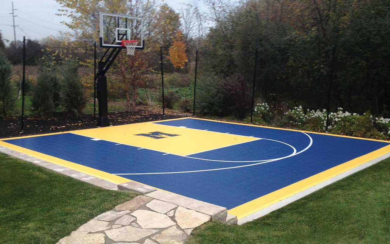 a blue and yellow basketball court with a basketball hoop in the backyard .
