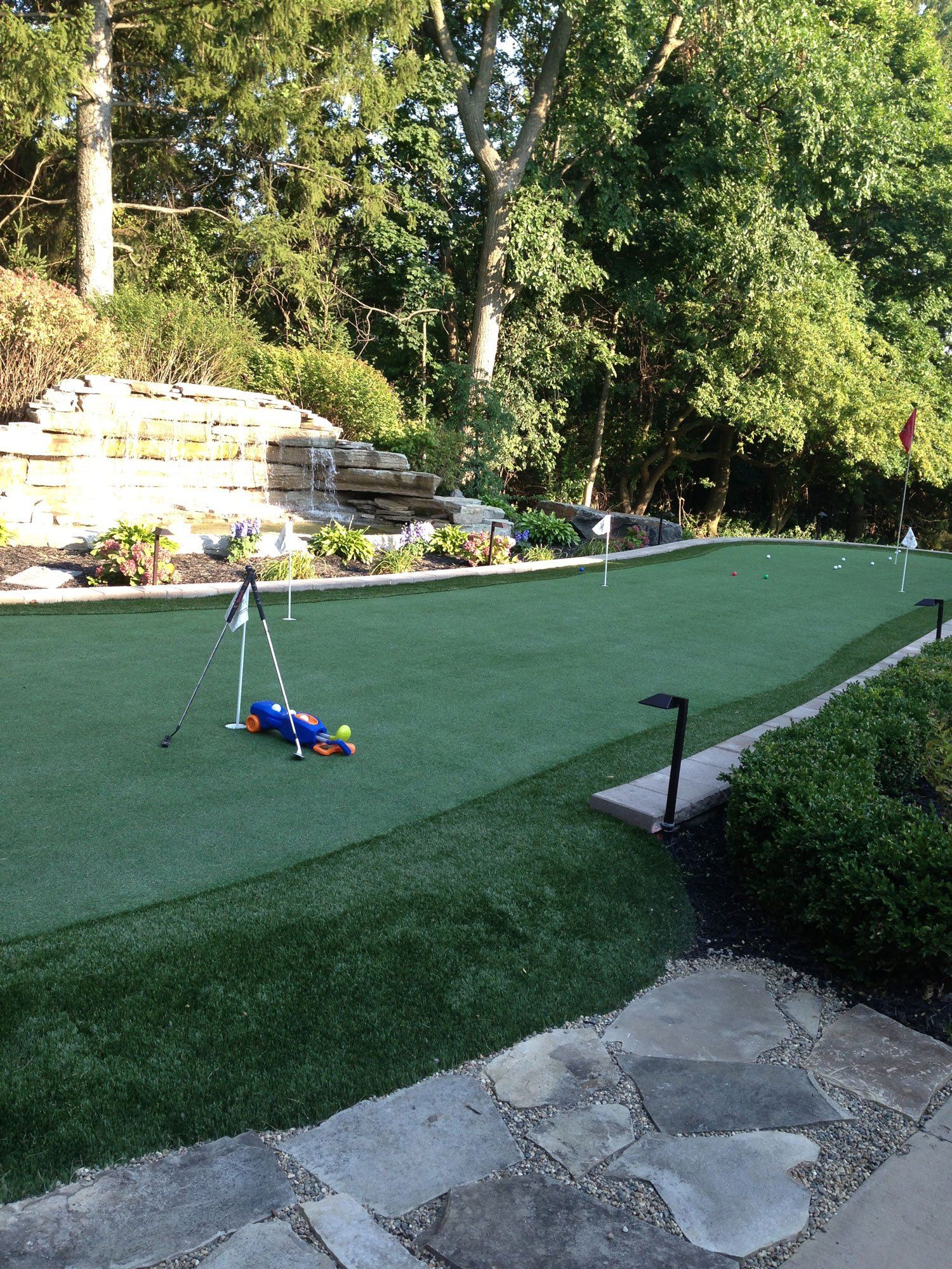 a putting green in a backyard with a waterfall in the background