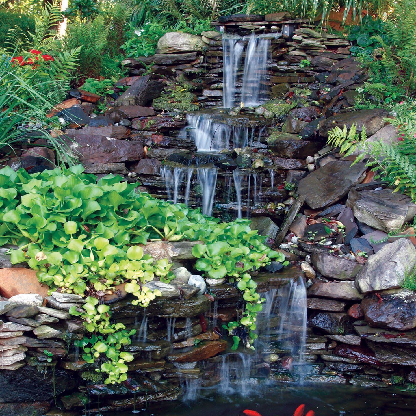 A waterfall surrounded by rocks and plants in a garden
