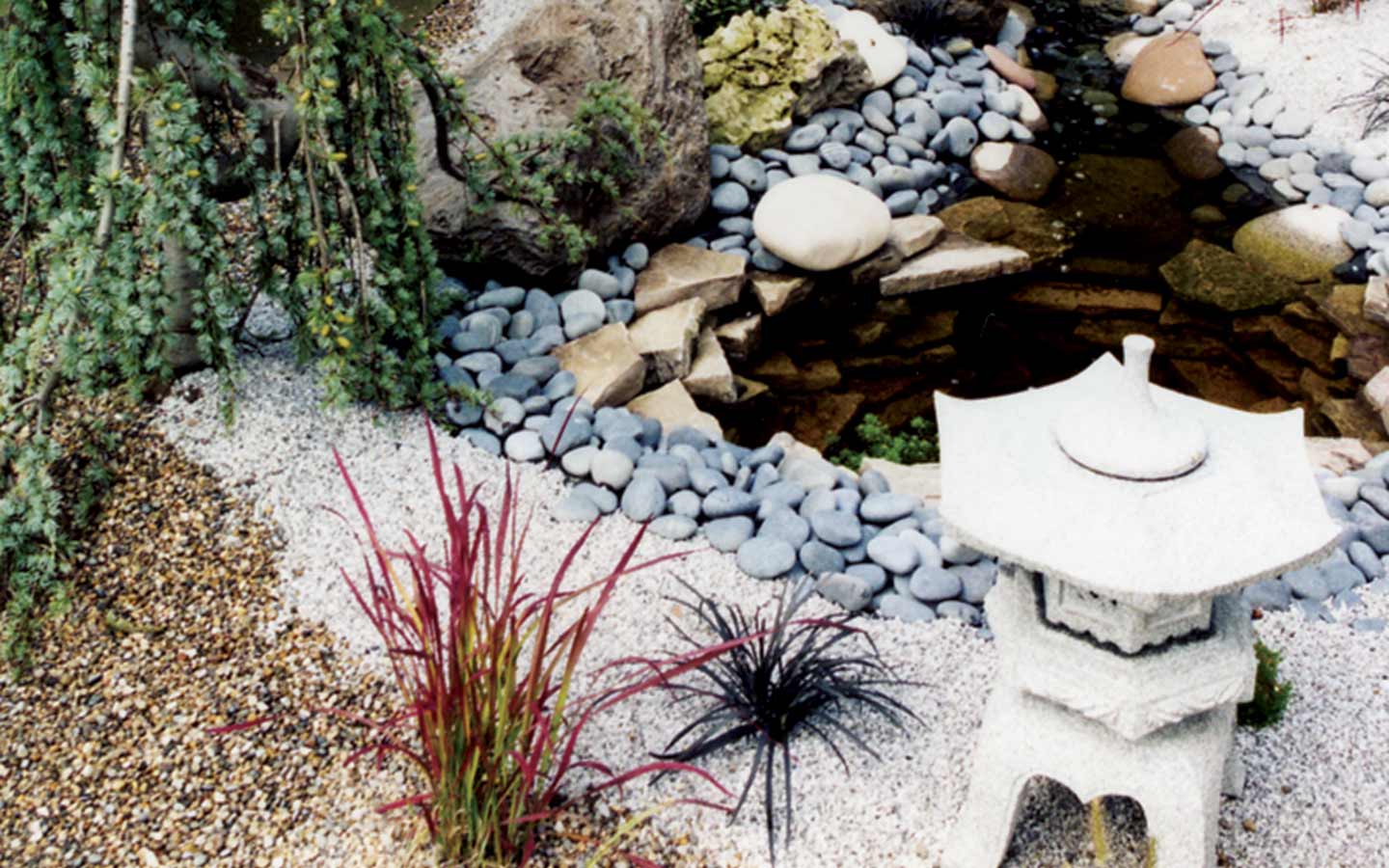 there is a lantern in the middle of a rock garden .