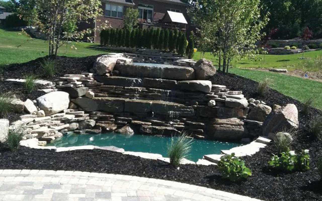 there is a waterfall in the middle of a lush green field .