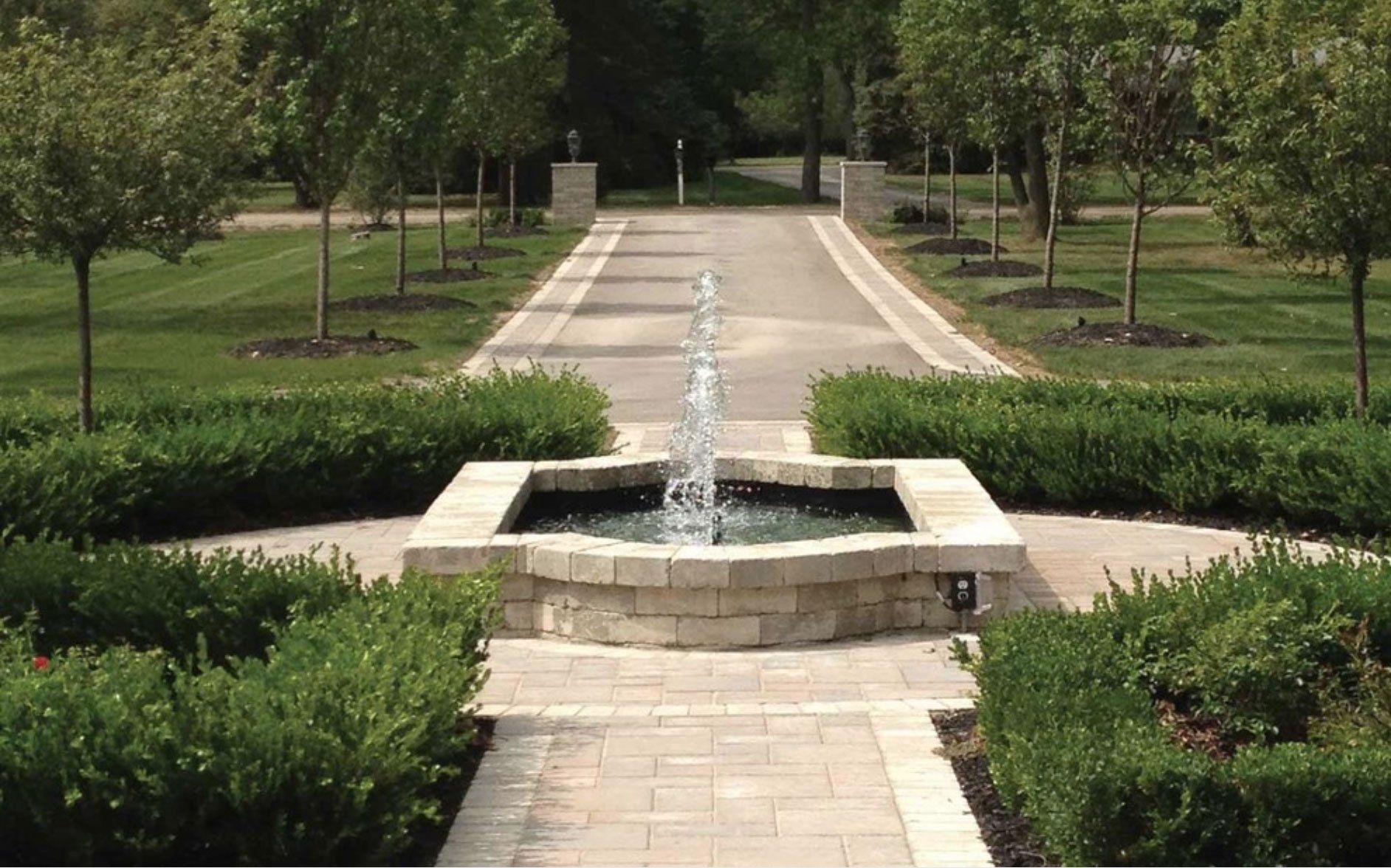 a fountain in the middle of a park surrounded by trees