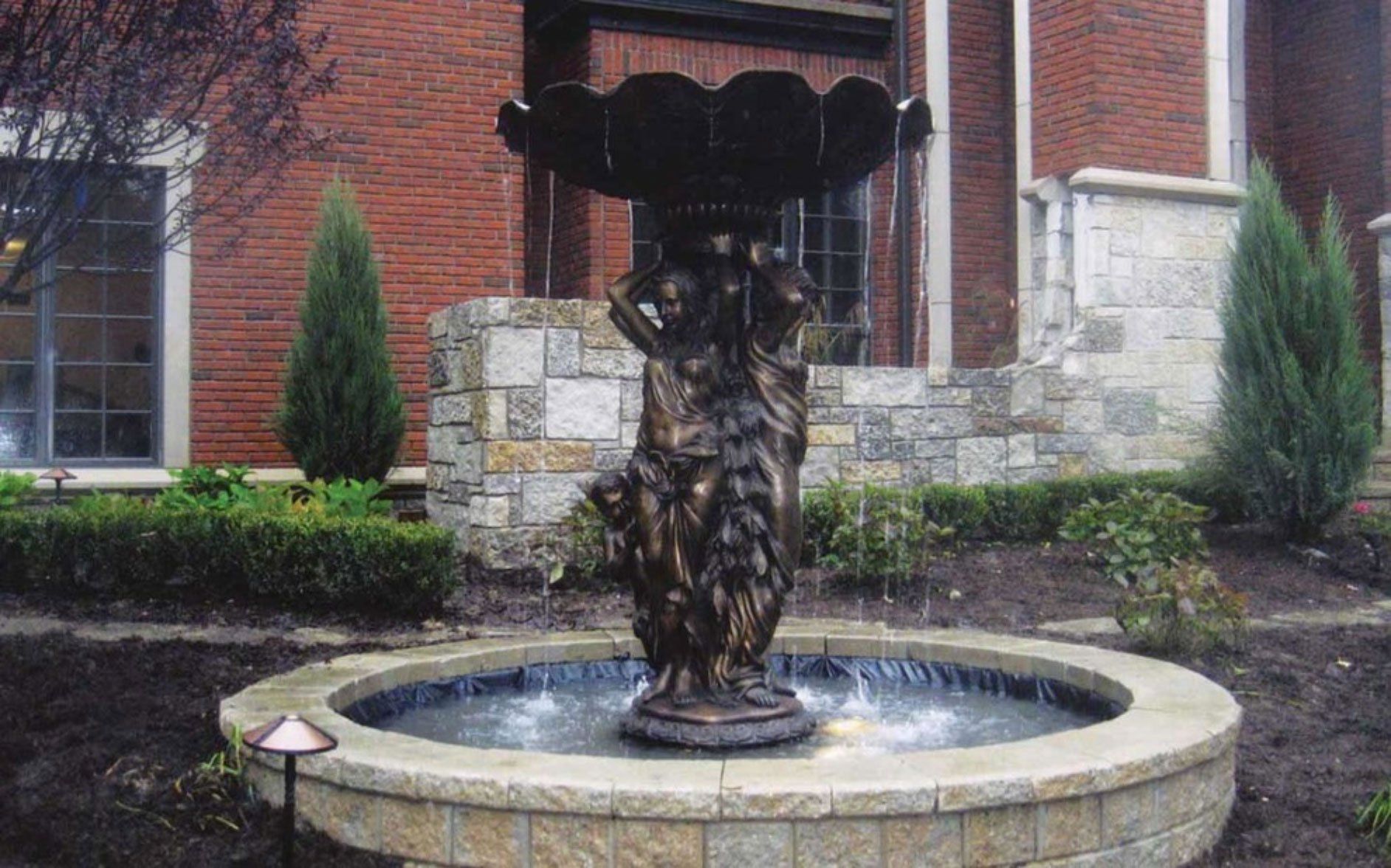 a large fountain in front of a brick building