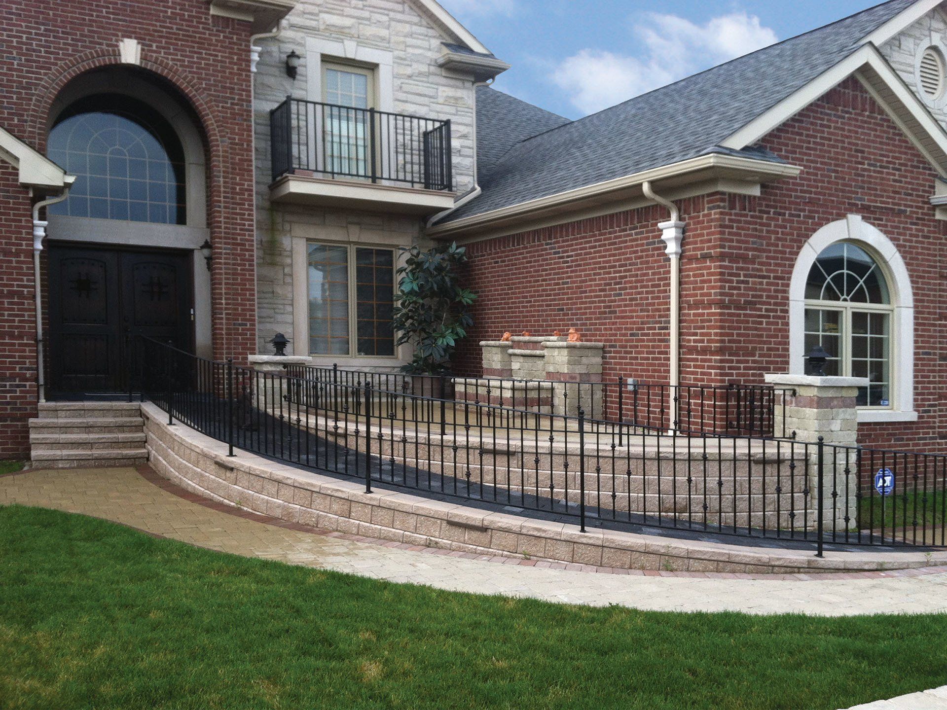 a large brick house with a wrought iron fence around it