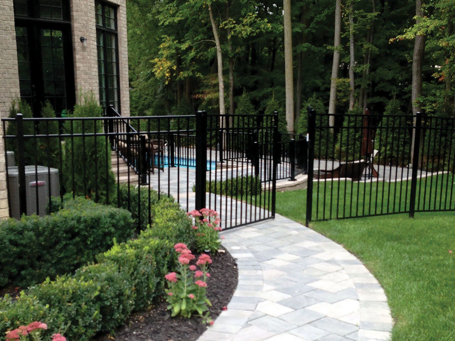 a walkway leading to a pool with a black fence