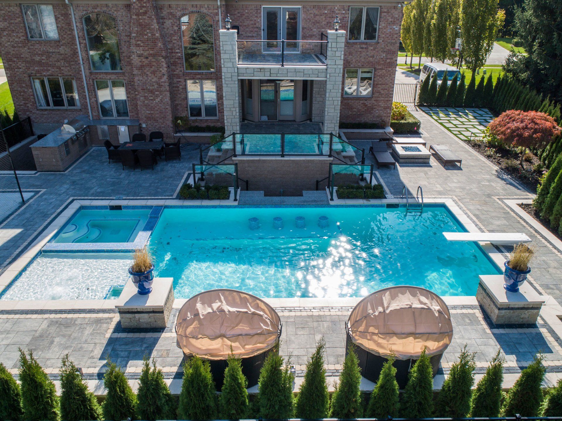 An aerial view of a large swimming pool in front of a large brick house.