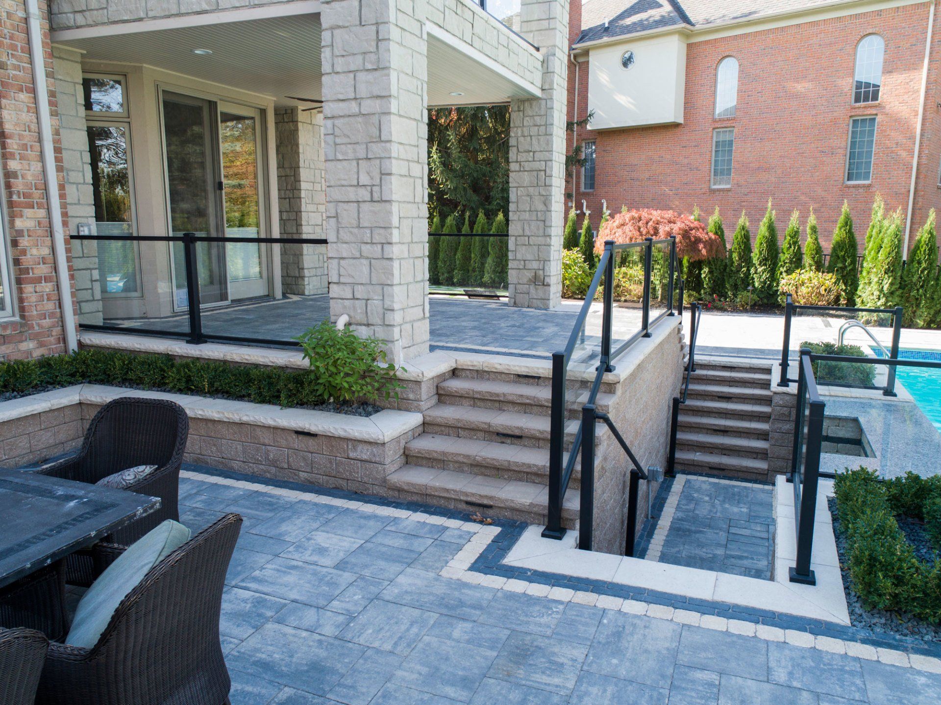 A patio with a table and chairs and stairs leading to a pool.