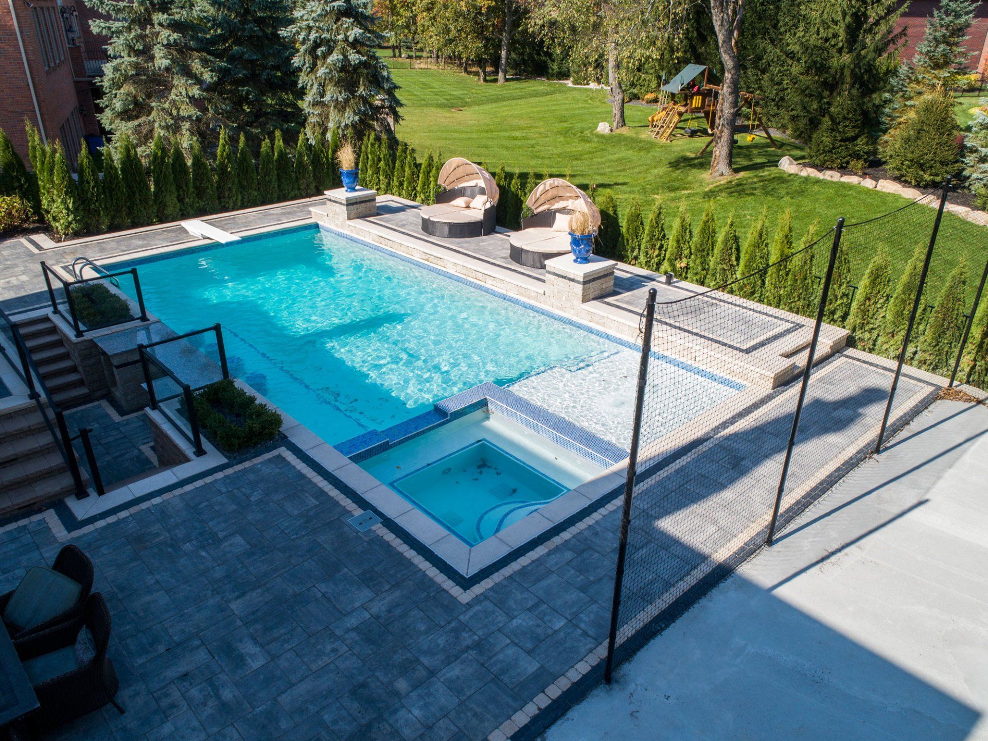 An aerial view of a large swimming pool in the backyard of a house.